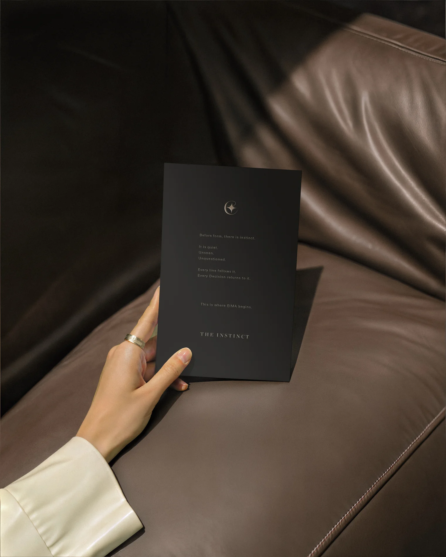 EIMA — the Instinct card held over a brown leather sofa