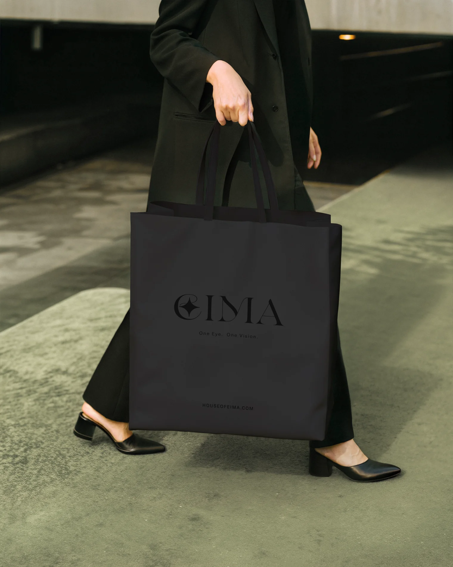 EIMA — a black branded tote, carried mid-stride