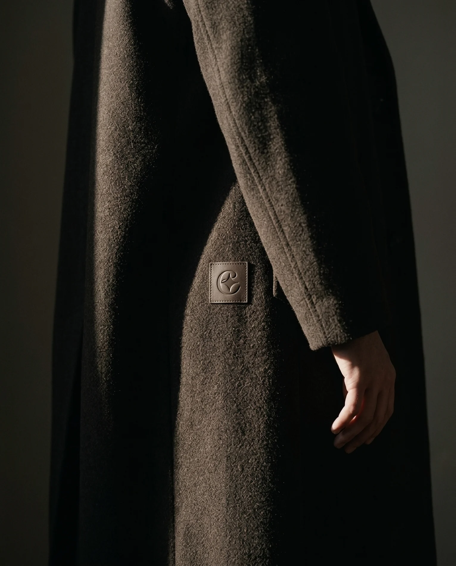 EIMA — the embossed leather monogram patch on a wool coat