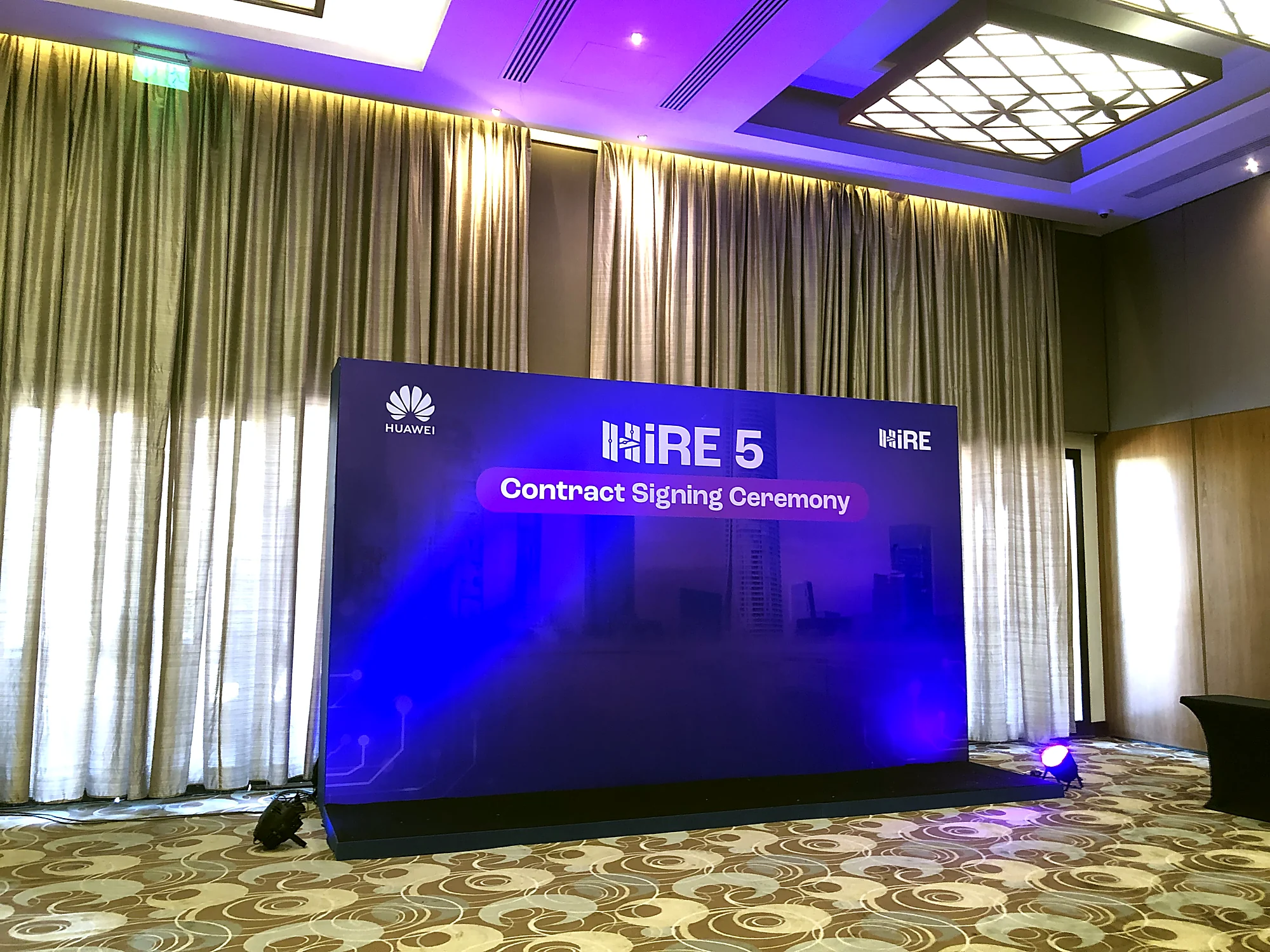 The HiRE 5 Contract Signing Ceremony stage, a blue-lit branded LED wall in the ballroom
