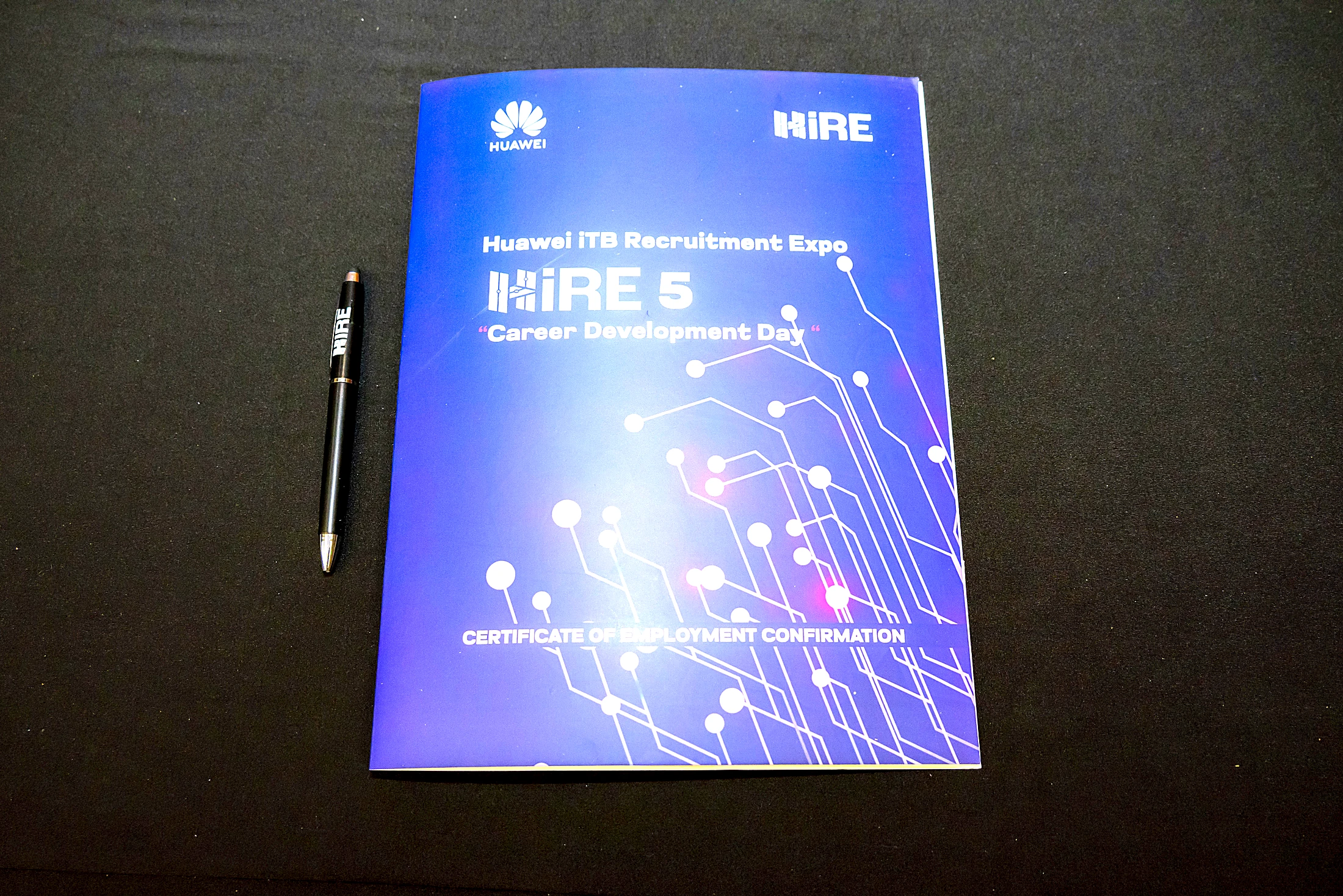 A HiRE 5 Certificate of Employment Confirmation booklet resting with a pen on a dark surface
