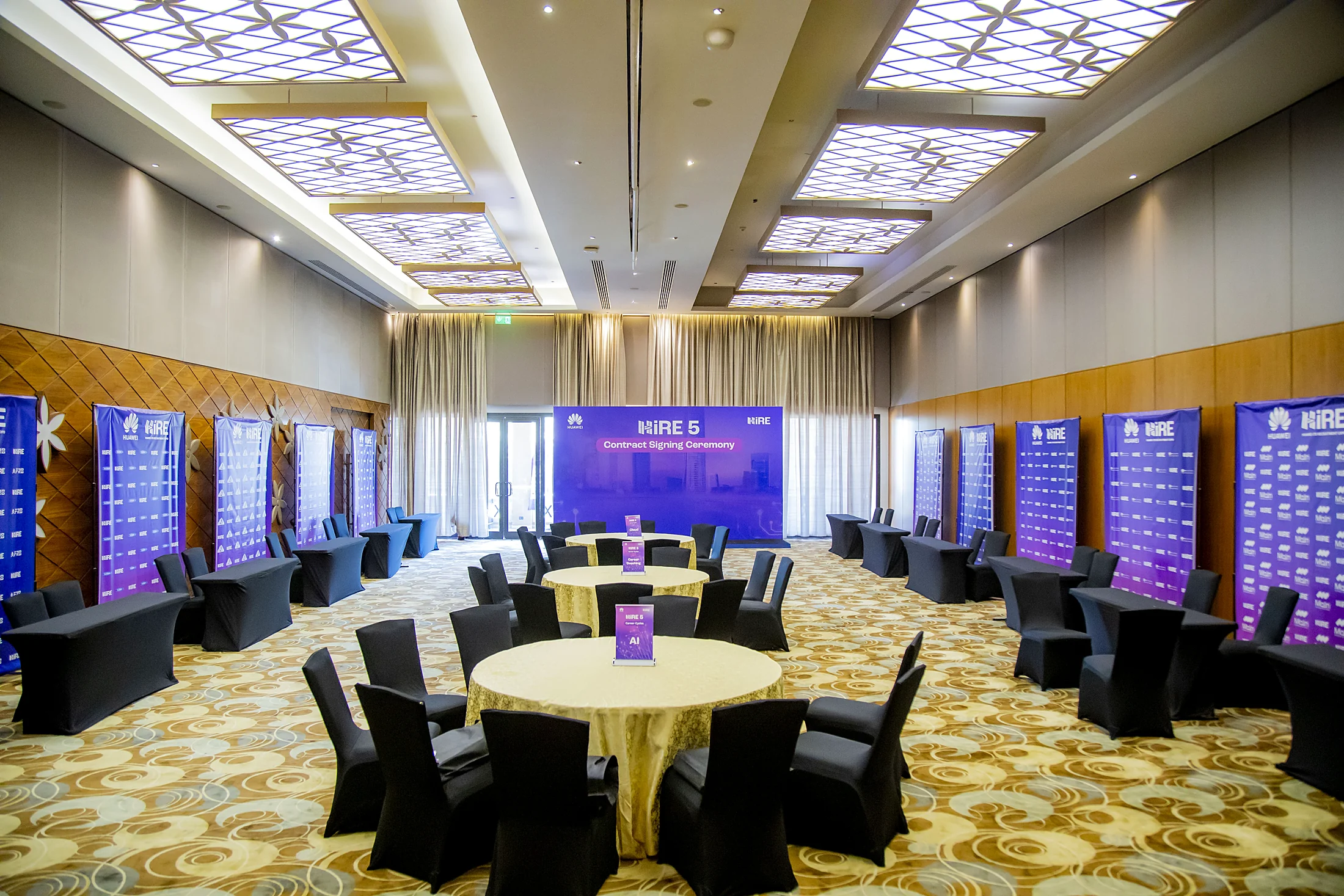 The banquet hall set with round tables, LED screens lining the walls