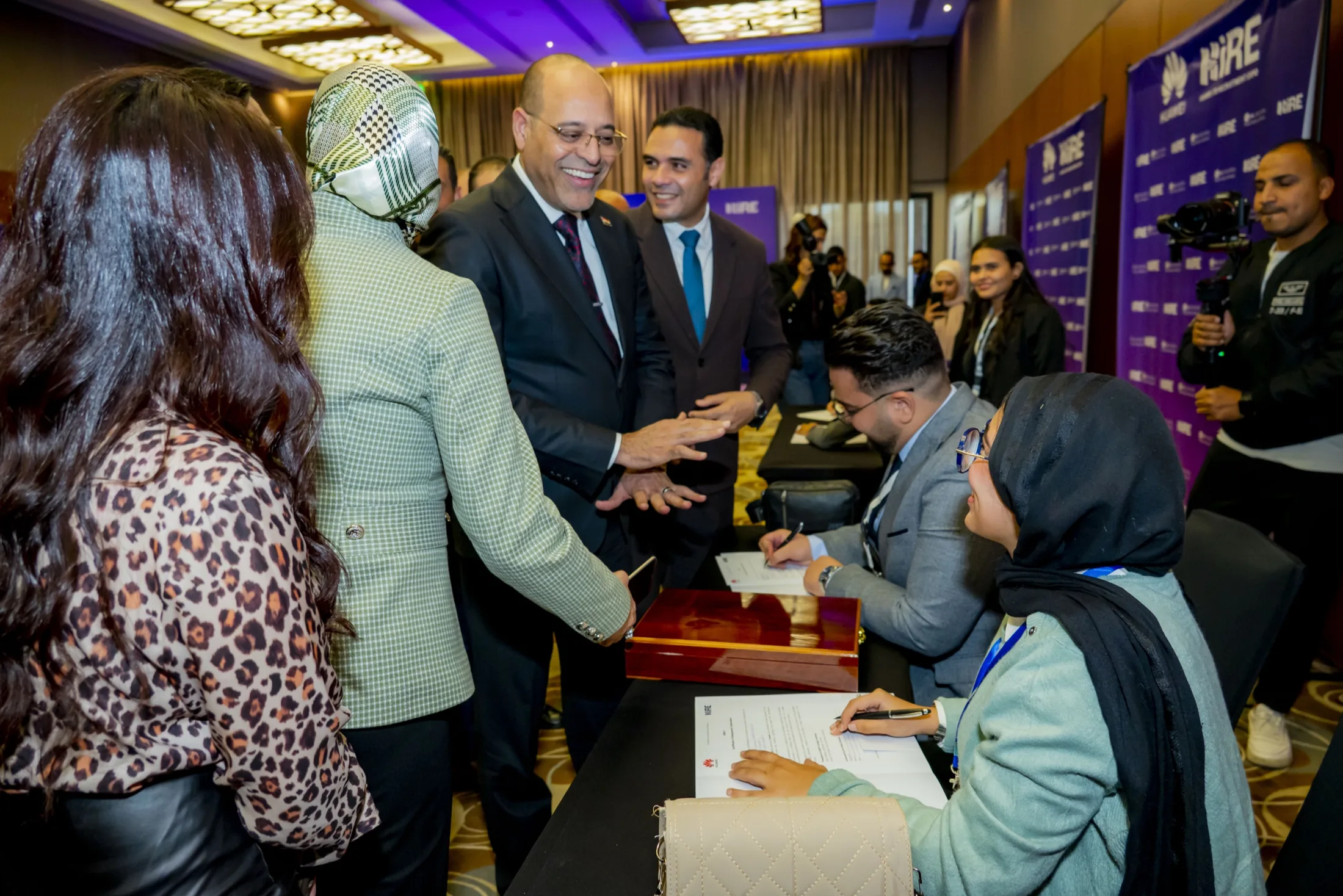 The Minister leaning in to greet young women applicants at a table