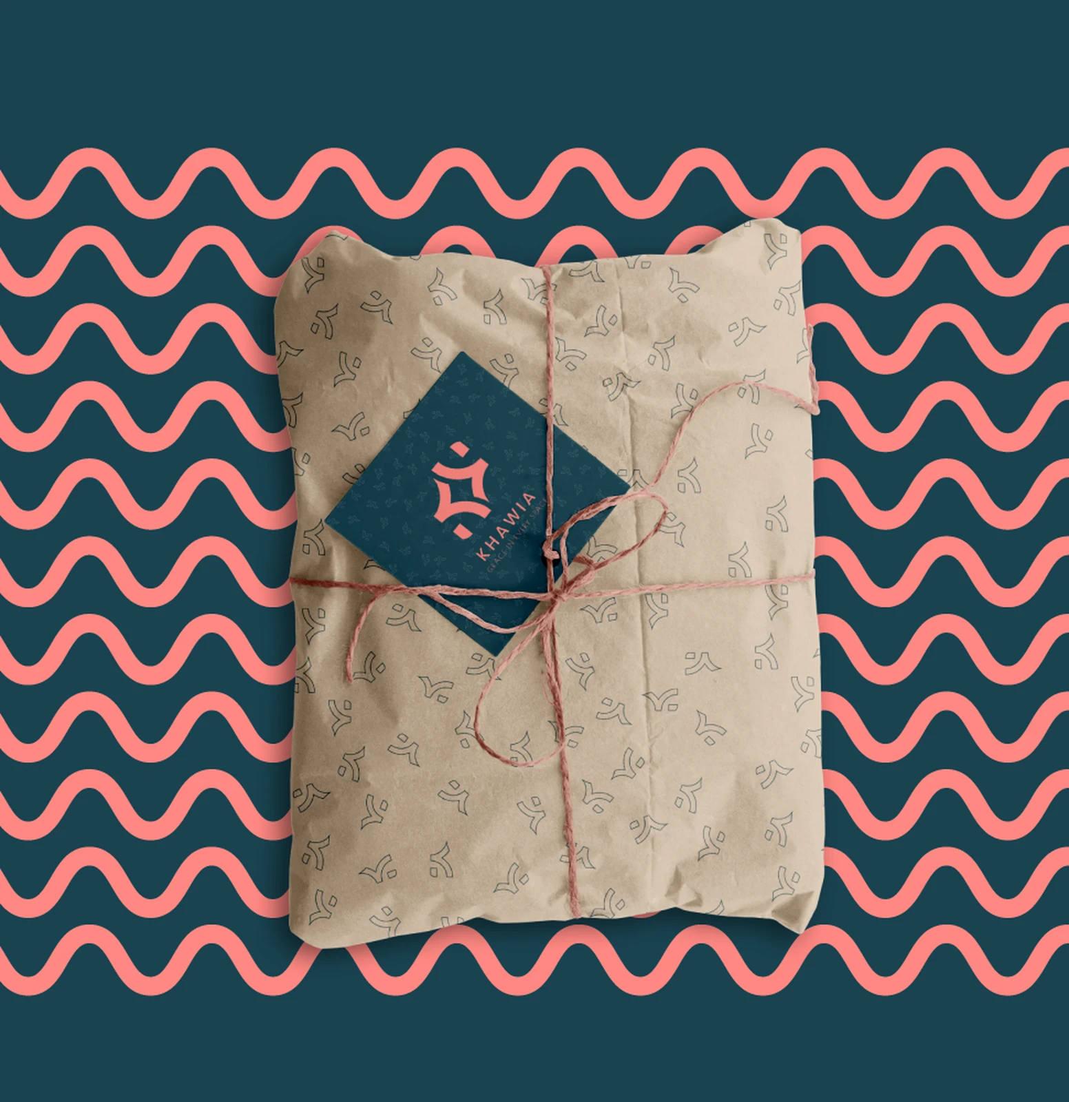Khawia packaging — a kraft parcel with a navy KHAWIA hang-tag and coral twine, on the wave