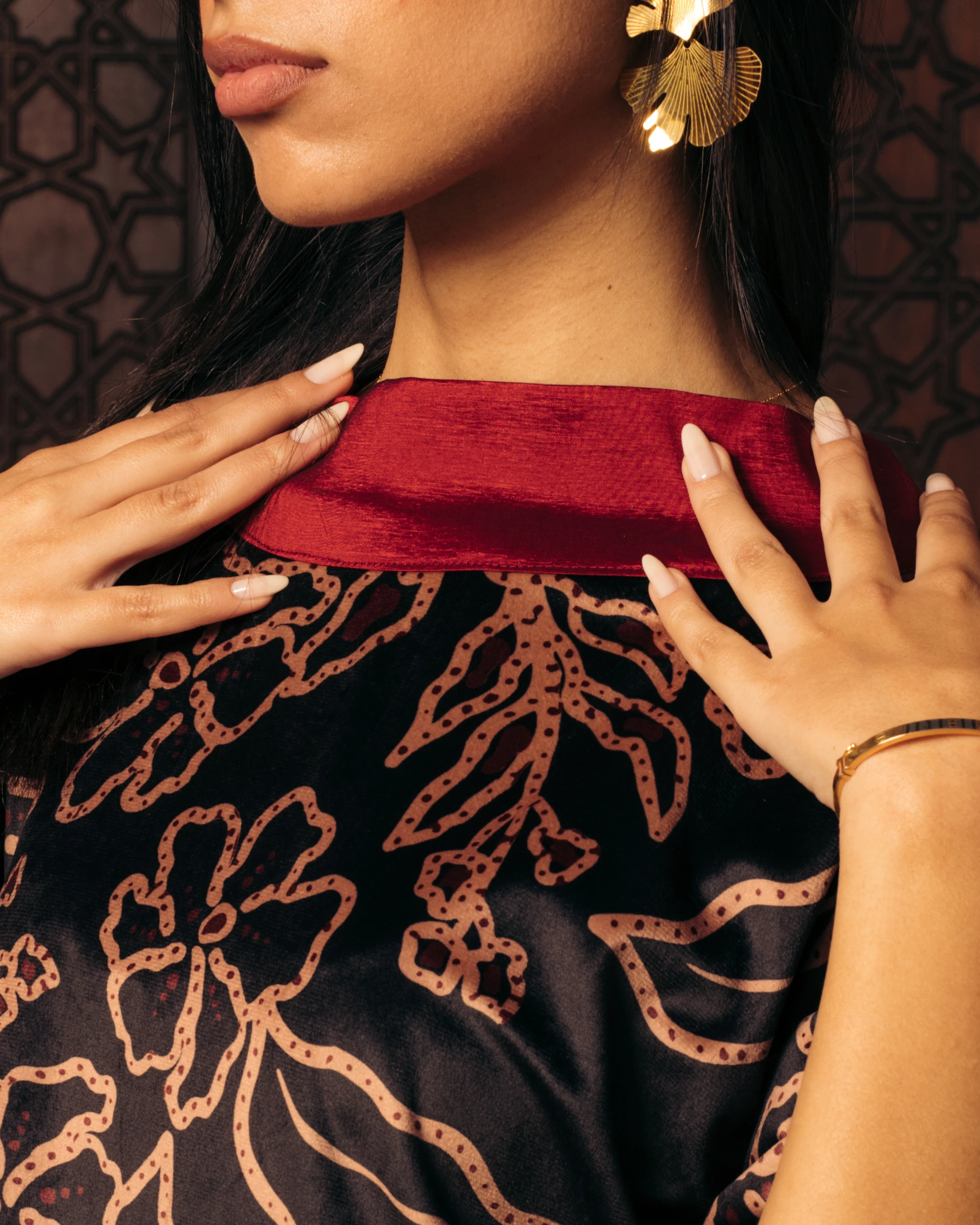 Khawia — a coral-embroidered black bodice, hand at the collar