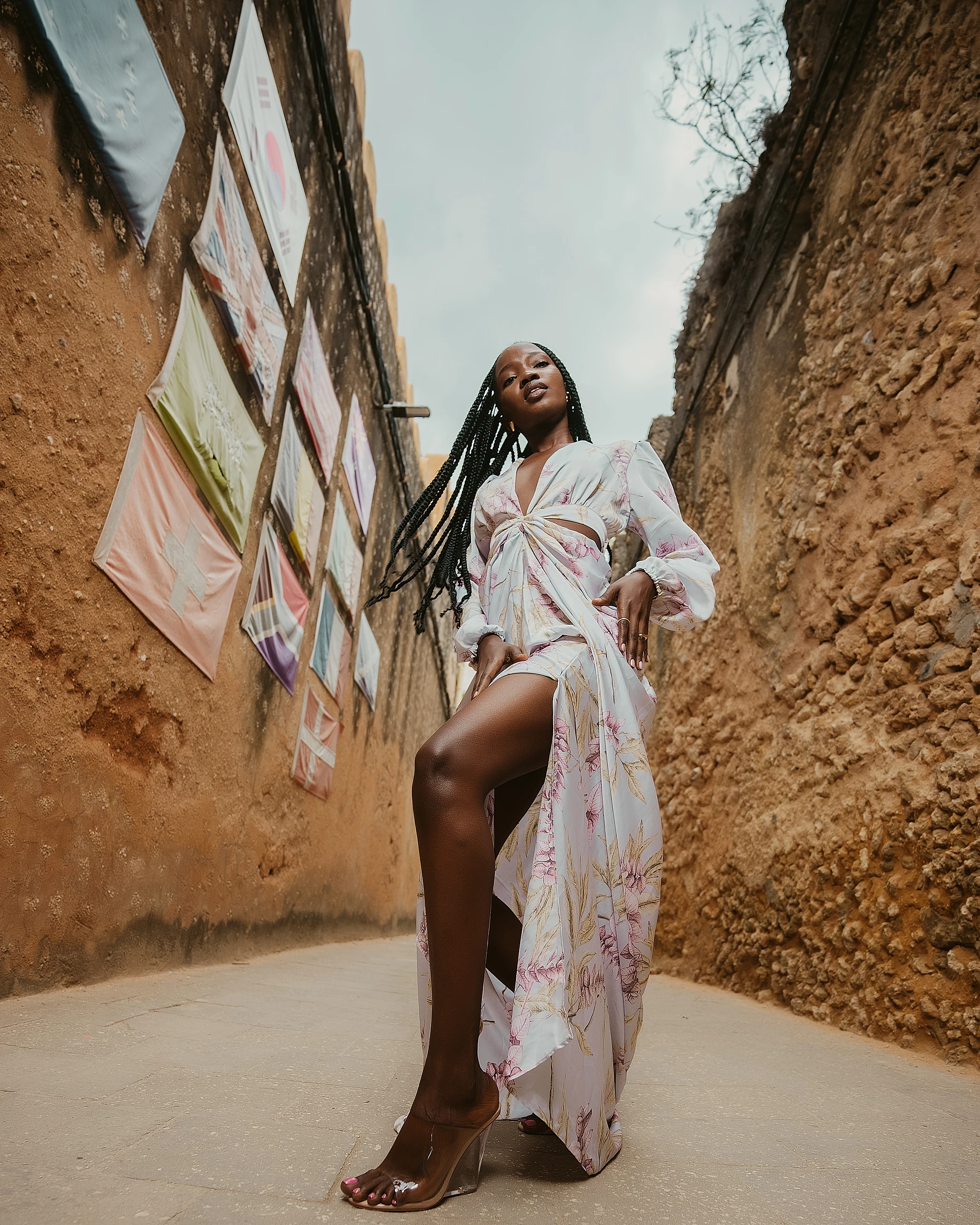 Khokha — a pastel print robe walking a sunlit ochre alley, Zanzibar